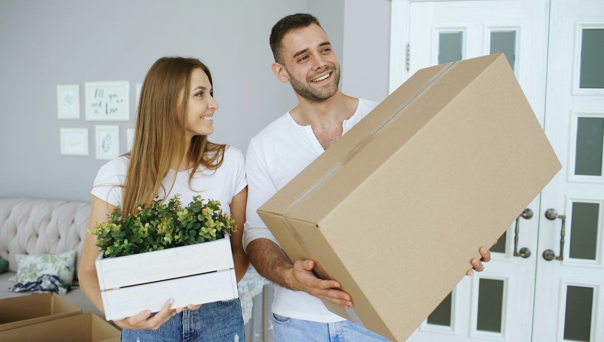 Couple qui transporte des boîtes dans son nouveau logement